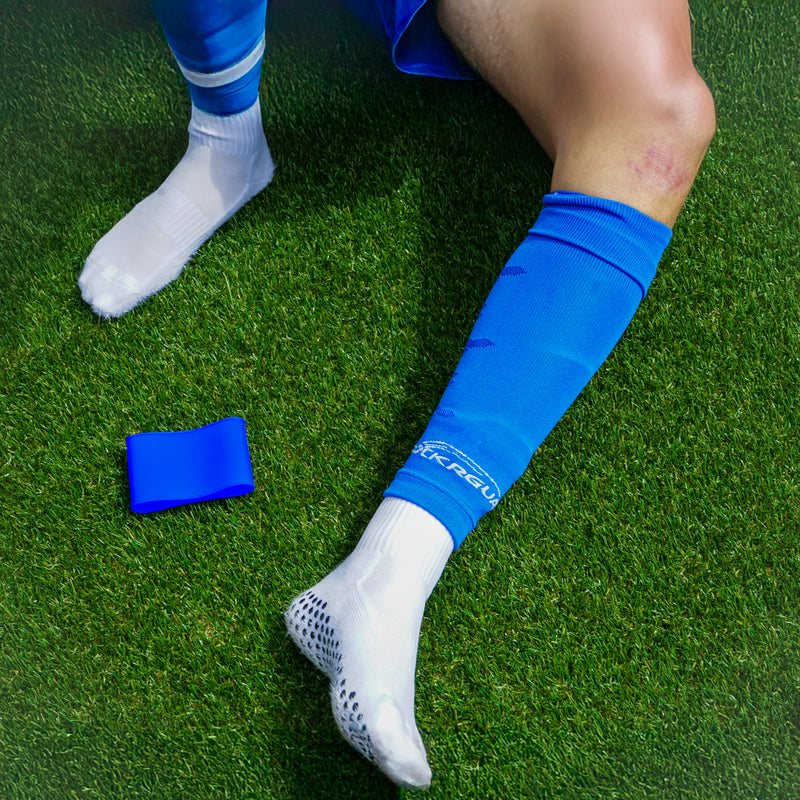 Scheenbeschermer bandje naast gripsokken en voetloze sokken op het veld