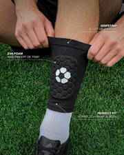 Speler trekt een ingebouwde scheenbeschermer aan op het veld, met de gripstrip en het EVA foam aangewezen
