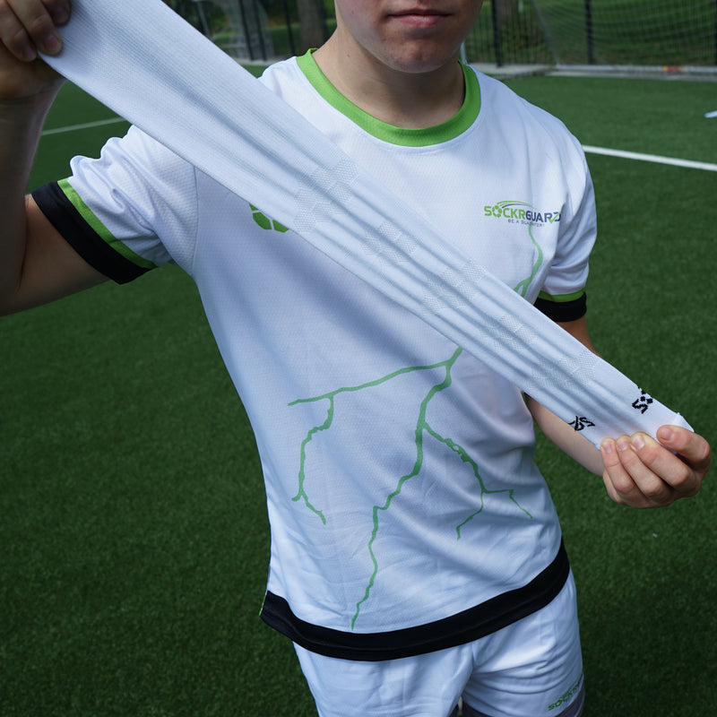 Voetballer rekt een witte voetbalsok zonder voet uit